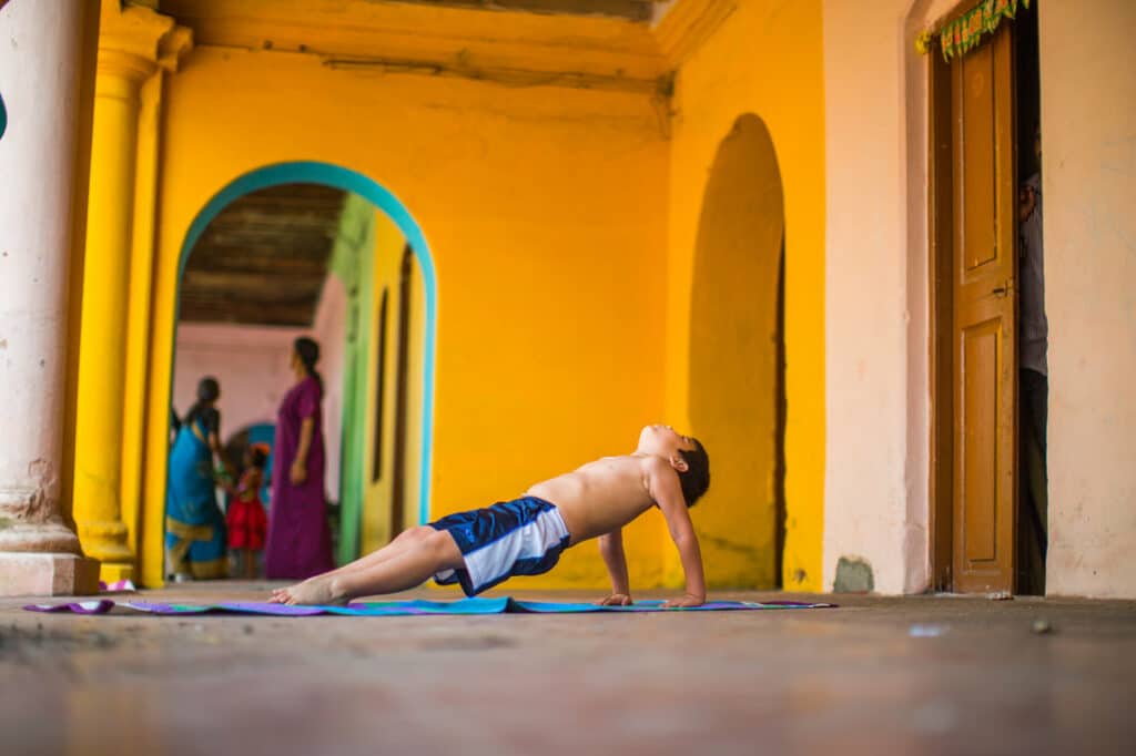 Krista Shirley's young son, Kaiden Park, is featured in an image demonstrating Purvottanasana, a seated pose from the Ashtanga Yoga primary series. Krista and Kaiden were in Mysore, India, where Krista continued her advanced yoga studies. Krista, the esteemed proprietor of The Yoga Shala located at 140 Circle Drive #4, Maitland, FL, is renowned for her specialization in traditional Ashtanga Yoga Mysore style teaching, alongside her expertise in rehabilitative body mechanics and mat pilates. Whether seeking guidance in-person or virtually, individuals can join Krista every weekday morning at The Yoga Shala. Additionally, Krista shares her wealth of knowledge and insights through her YouTube channel (youtube.com/@yogawithkrista), assisting people in establishing and nurturing a safe and enriching at-home yoga practice.