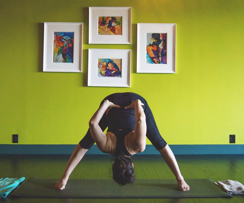 In the Yoga Shala located at 140 Circle Drive #4, Maitland, FL, the image depicts a morning Mysore style Ashtanga yoga class led by level two authorized teacher Krista Shirley. The main focus is on a female yoga student performing the full expression of Prasarita Padottanasana B, also known as Wide Leg Forward Fold Pose. Krista specializes in the traditional teaching of Ashtanga Yoga Mysore style. Additionally, she manages a YouTube channel titled "Yoga with Krista" (youtube.com/@yogawithkrista), offering guidance to students in establishing their at-home yoga practice. Whether in-person or virtually, individuals can engage with Krista every weekday morning at the Yoga Shala.