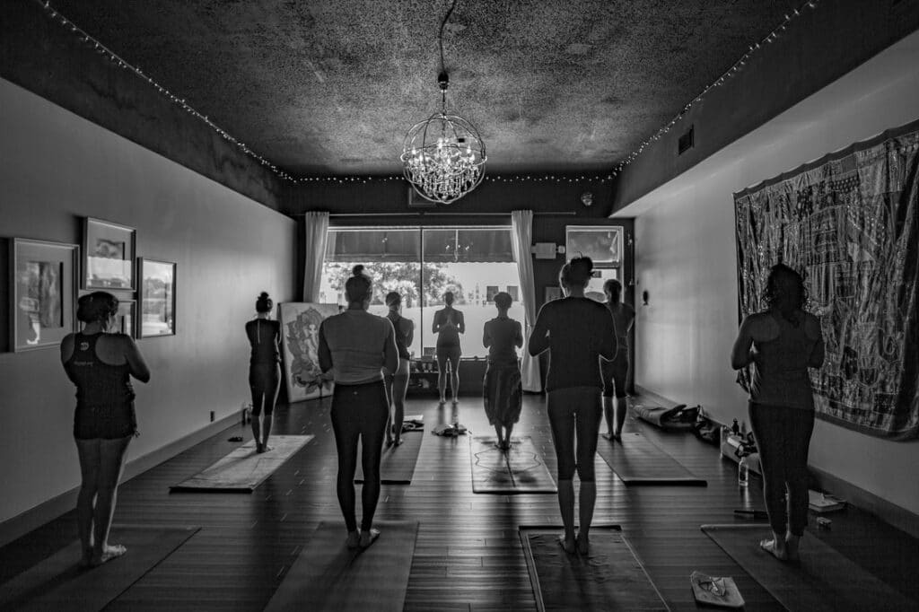 Owner Krista Shirley leads a Mysore style Ashtanga Yoga class at the Yoga Shala in Maitland, Florida. Students stand at the top of their mats, chanting the Ashtanga Yoga opening mantra alongside Krista. The studio, located at 140 Circle Drive #4, offers classes accessible to practitioners of all levels, led by Krista, a Level Two authorized Ashtanga Yoga teacher.