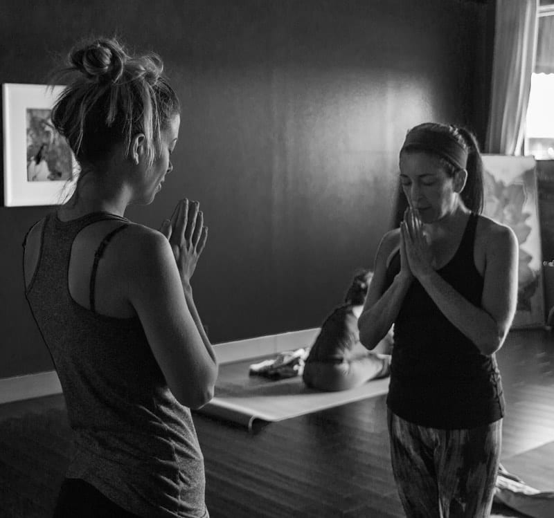 In the Yoga Shala at 140 Circle Drive #4, Maitland, Florida, an Ashtanga Yoga teacher leads a student in chanting the Ashtanga Yoga opening mantra. The student stands at the top of her mat, joining in the sacred chant. The Yoga Shala offers Mysore style Ashtanga Yoga classes every weekday morning, welcoming practitioners of all levels to begin their yoga journey with dedication and reverence.